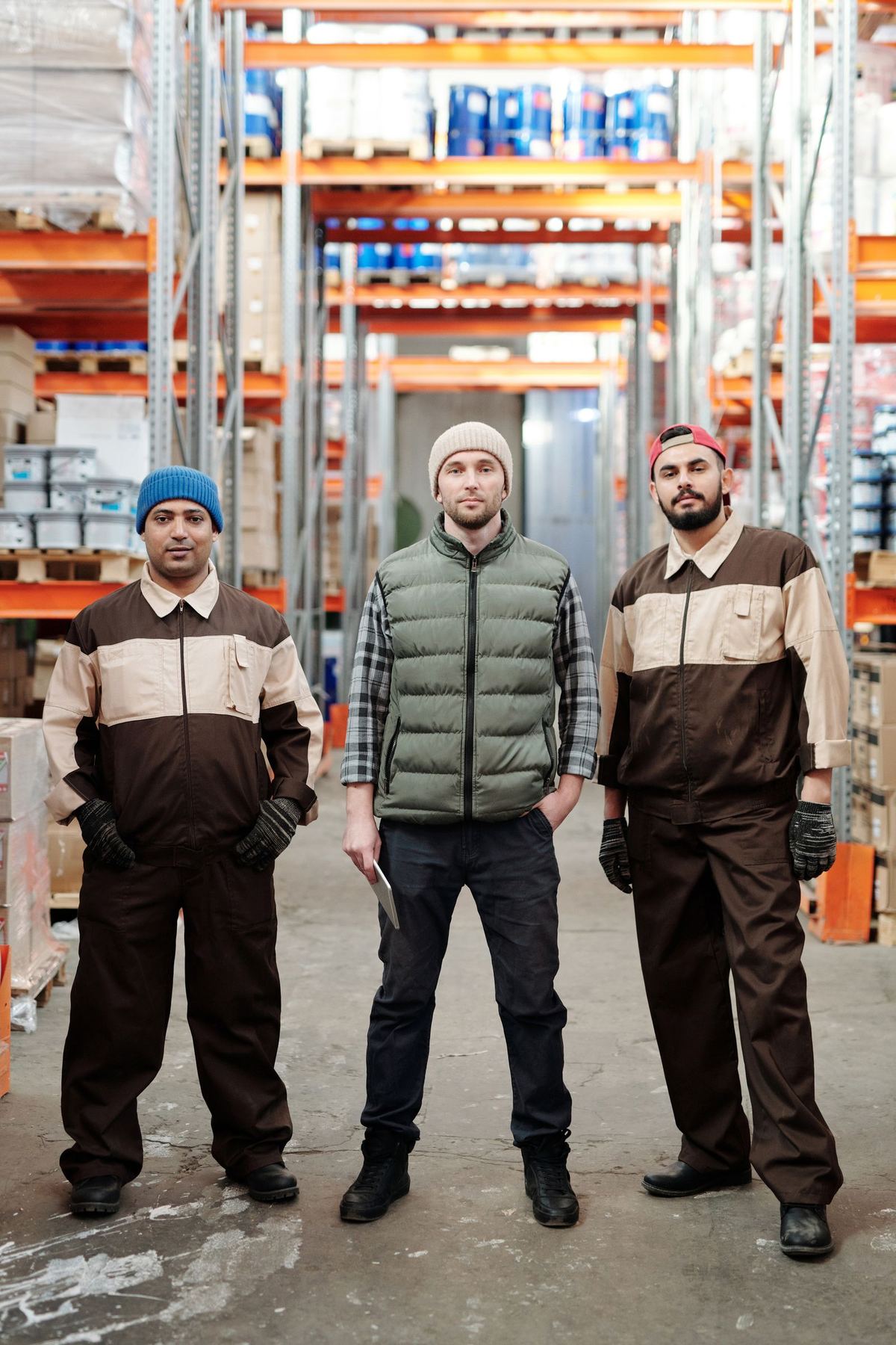 Three warehouse staff standing together in a storage aisle